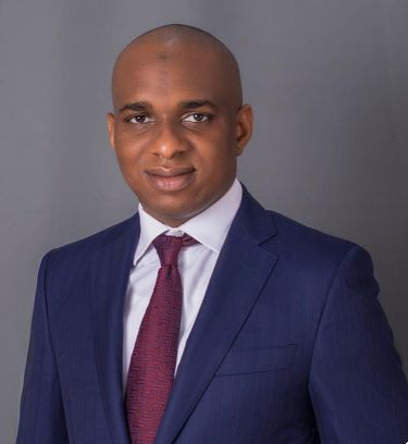 Professional portrait of a politician in a navy suit and maroon tie.