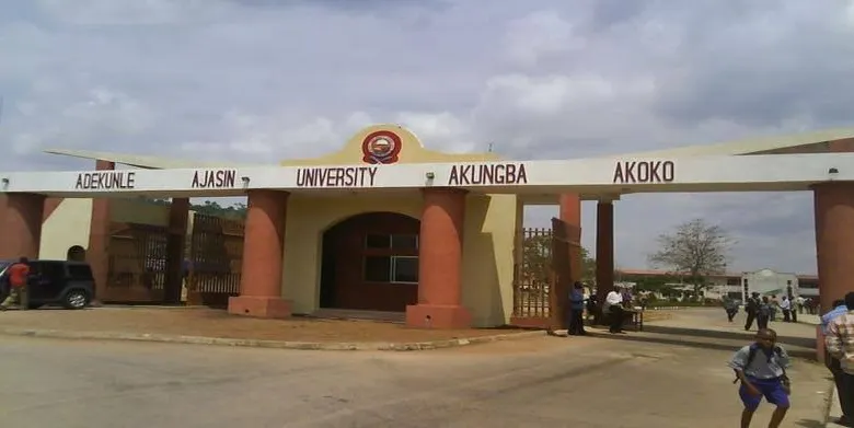 Entrance gate of Ondo State University with students and vehicles in front.
